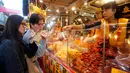 Pengunjung mencicipi makanan ringan saat berbelanja persiapan Tahun Baru Imlek di pasar Dihua Street di Taipei, Selasa (29/1). Warga Taiwan mulai berburu makanan lezat, kue kering dan barang- lainnya di pasar menjelang Imlek. (AP/Chiang Ying-ying)