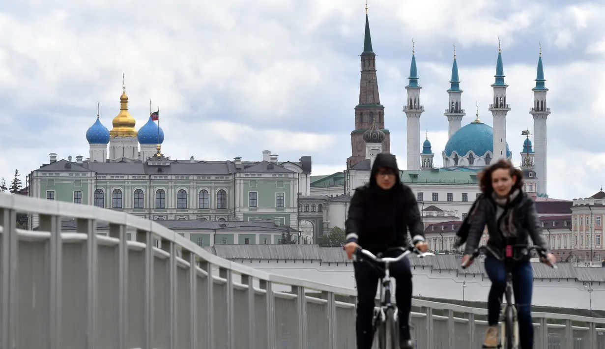 Pesepeda melintas di atas jembatan sungai Kazanka dengan latar belakang masjid Kul-Sharif di Kazan, Rusia, 9 Juni 2018. Masjid yang selalu ramai ini tidak hanya sebagai tempat ibadah, namun juga sebagai museum dan Islamic Center. (AFP PHOTO/SAEED KHAN)