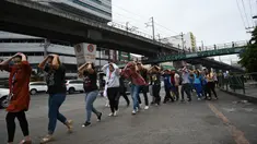Karyawan call center melindungi kepalanya sambil berjalan saat mengikuti latihan gempa di Manila (14/11/2019). Latihan ini sebagai bagian dari kesiapsiagaan nasional menyusul berbagai gempa yang melanda pulau Mindanao bulan lalu. (AFP Photo/Ted Aljibe)