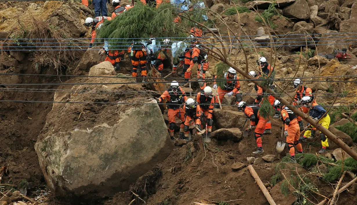 Petugas penyelamat dan polisi melakukan evakuasi di sekitar lokasi terjadinya longsor yang menghantam rumah hunian di Nakatsu, Prefektur Oita, Jepang (11/4). Diyakini enam orang tertimbun longsor. (AFP Photo/Jiji Press/Japan Out)