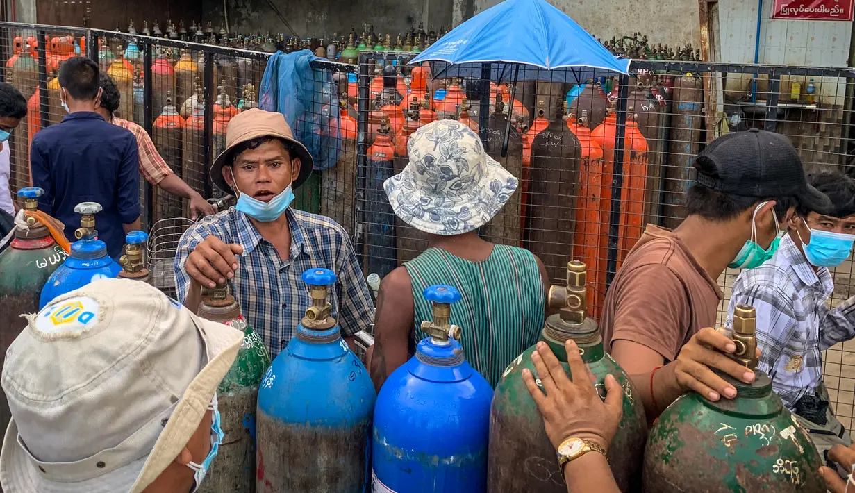 Gambar pada 14 Juli 2021 ini menunjukkan orang-orang yang menunggu untuk mengisi tabung oksigen kosong di luar sebuah pabrik di Yangon, di tengah lonjakan kasus virus coron Covid-19. Warga di seluruh kota terbesar Myanmar menentang jam malam militer. (Ye Aung THU/AFP)