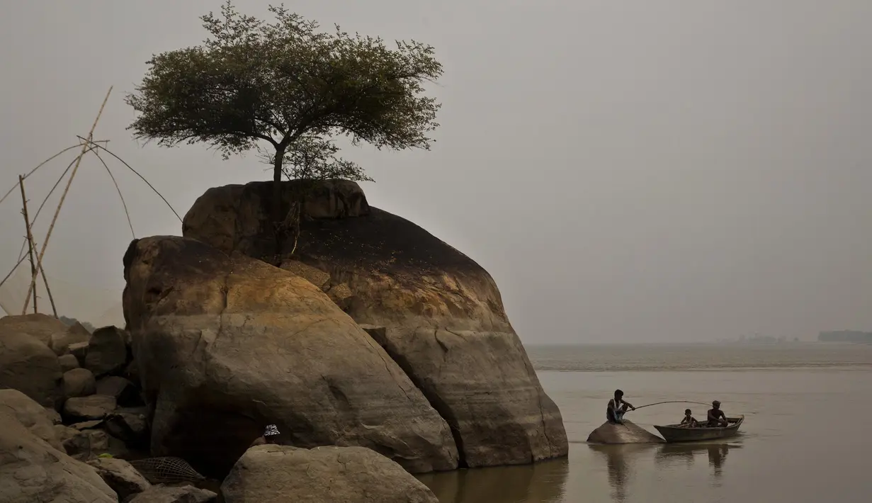Seorang nelayan duduk di atas batu menangkap ikan di sungai Brahmaputra di desa Kasoshila di Gauhati, India (21/10/2019). Brahmaputra adalah salah satu sungai terbesar di Asia, yang melewati wilayah Tibet China, India, dan Bangladesh sebelum konvergen ke Teluk Benggala. (AP Photo/Anupam Nath)