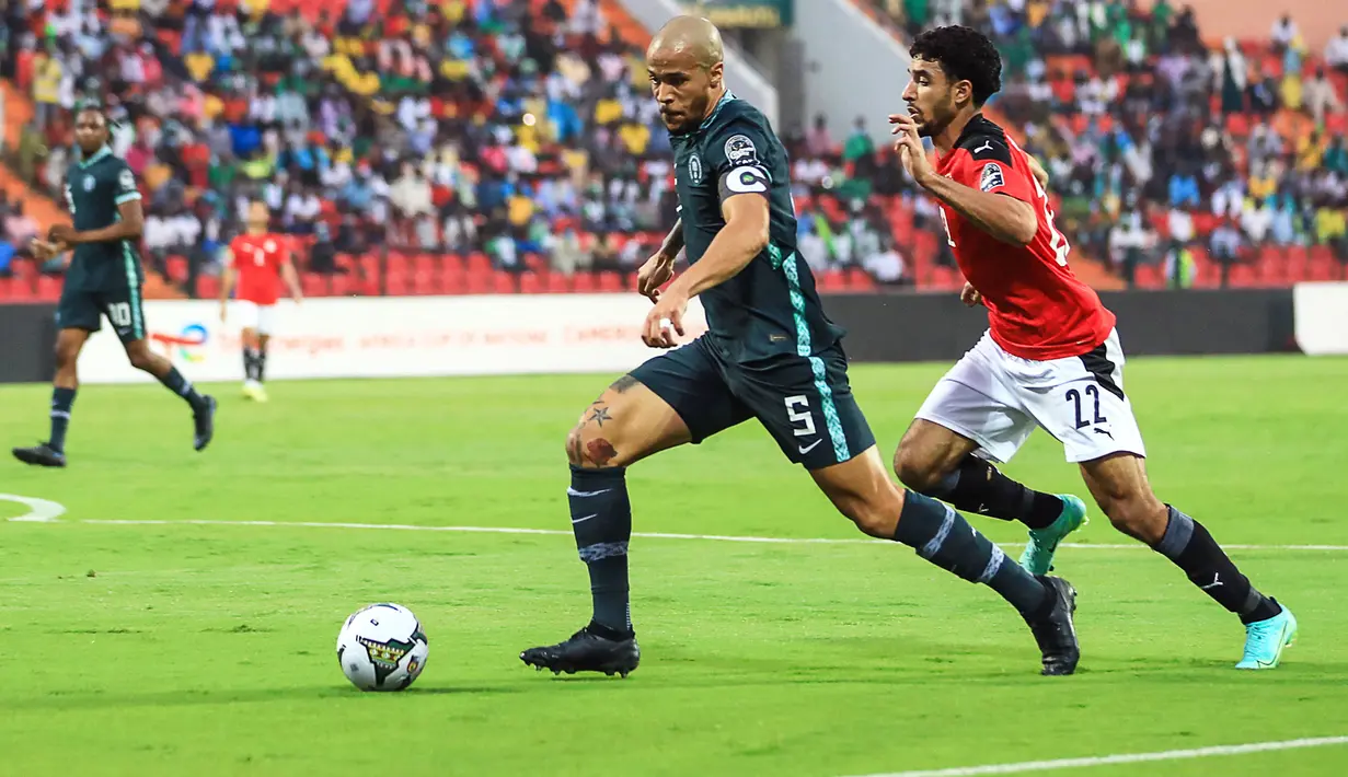 Bek Nigeria, William Troost-Ekong (kiri) berebut bola dengan penyerang Mesir, Omar Marmoush selama pertandingan Grup D Piala Afrika (CAN) 2021 di Stade Roumde Adjia di Garoua (12/1/2022). Nigeria menang tipis atas Mesir tipis 1-0 lewat gol Kelechi Iheanacho. (AFP/Daniel Beloumou Olomo)
