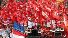Sejumlah buruh membawa bendera berwarna merah saat aksi May Day 2016 di Jakarta, Minggu (1/5). Kaum buruh mengajukan tuntutan menolak upah murah serta pencabutan PP No. 78 Tahun 2015. (Liputan6.com/Angga Yuniar)