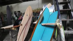 Seorang pria merapihkan papan selancar di sebuah pabrik dekat Kuta di pulau Bali (18/12). Biasanya, pengerjaan sebuah papan surfing memakan waktu hingga dua minggu tergantung ukuran. (AFP Photo/Sonny Tumbelaka)