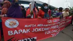 Warga Kampung Sawah membentangkan spanduk saat melakukan aksi dengan menutup akses jalan Cakung Cilincing, Jakarta, Rabu (18/11/2020). Aksi tutup jalan ini bentuk protes warga atas hak tanahnya yang terkena proyek pembangunan jalan tol Cakung Cilincing (Cacing)-Cibitung. (merdeka.com/Imam Buhori)