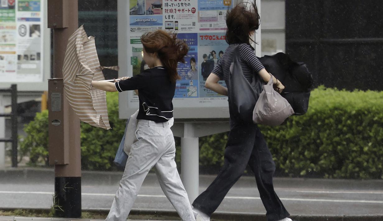 Orang-orang berjalan di tengah hujan badai yang dibawa oleh Badai Tropis Khanun di Kagoshima, Jepang selatan Rabu, 9 Agustus 2023. (Kyodo News via AP)