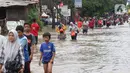 Warga melintasi banjir yang menggenangi Jalan KH Hasyim Ashari, Tangerang, Banten, Kamis (2/1/2020). Banjir yang menggenangi jalan penghubung Jakarta- Tangerang tersebut mulai surut dan sudah bisa dilintasi pejalan kaki. (Liputan6.com/Angga Yuniar)
