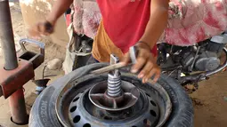 Seorang anak memperbaiki ban di distrik Abs utara di provinsi Haji Yaman, (8/5). Menurut badan anak-anak PBB jumlah anak-anak tanpa akses ke pendidikan menjadi dua juta, karena anak di bawah umur direkrut untuk bertempur. (AFP Photo/Essa Ahmed)