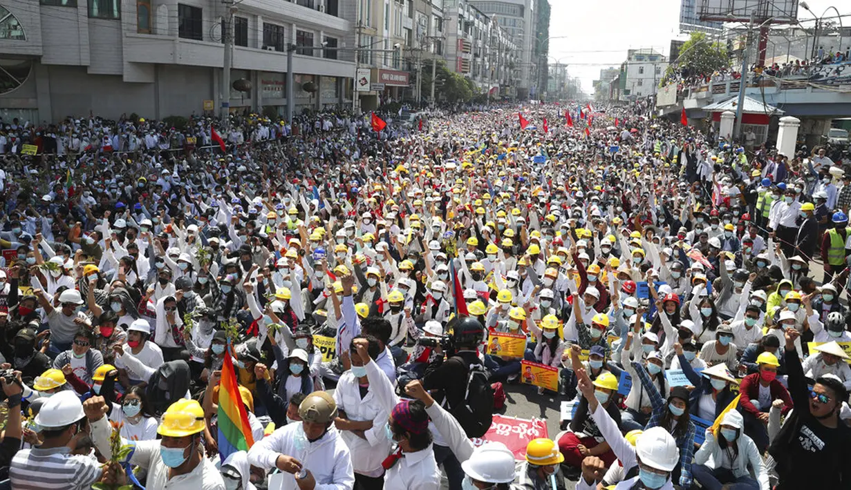 Pengunjuk rasa antikudeta mengangkat tangan terkepal selama demonstrasi dekat Stasiun Kereta Api Mandalay di Mandalay, Myanmar, Senin (22/2/2021). Junta militer Myanmar memberi peringatan kepada demonstran bahwa mereka terancam kehilangan nyawa jika terus beraksi. (AP Photo)