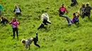 Peserta berlomba mengejar keju dalam kompetisi Cheese Rolling di Bukit Cooper, Gloucestershire, Inggris, Senin (27/5/2019). Ada lima sesi kompetisi balapan menggelindingkan keju dalam festival ini, yaitu 4 sesi untuk pria dan satu sesi untuk wanita. (Ben Birchall/PA via AP)
