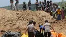Warga menyaksikan pemakaman massal jenazah korban gempa dan tsunami di Palu, Sulawesi Tengah, Senin (1/10). Gempa dan tsunami yang melanda Palu serta Donggala telah menewaskan ratusan korban jiwa. (AP Photo/Tatan Syuflana)