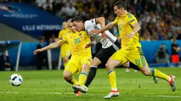 Gelandang Jerman, Mesut Ozil (tengah) berusaha melewati dua pemain Ukraina di kualifkasi grup C Piala Eropa 2016 di Stadion Stade Pierre-Mauroy, Perancis, (12/6). Jerman menang atas Ukraina dengan skor 2-0. (REUTERS/Gonzalo Fuentes)