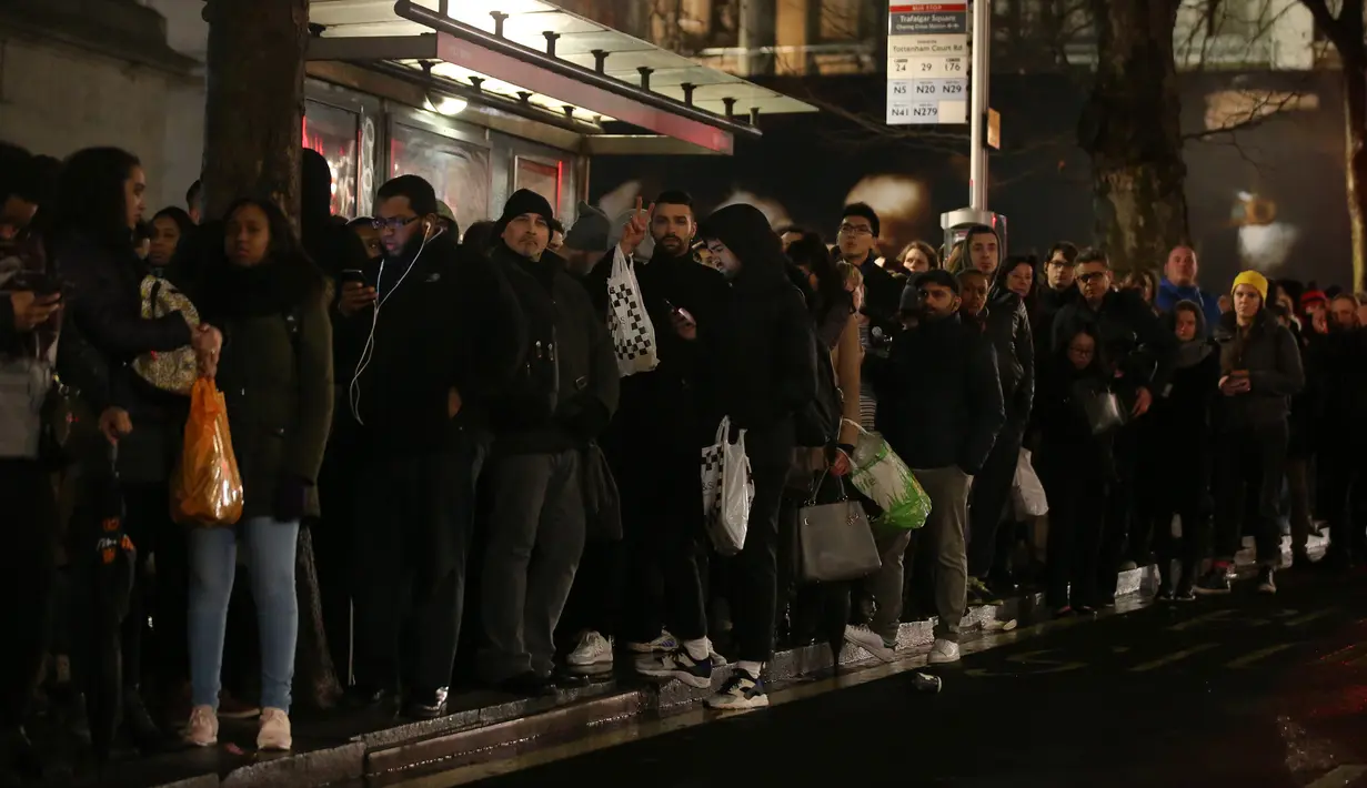 Para pengguna komuter antre menunggu bus di dekat stasiun kereta bawah tanah Charing Cross, London, Senin (9/1). Aksi mogok para pekerja kereta bawah tanah London mengakibatkan kekacauan di hampir semua stasiun. (Daniel Leal-Olivas/AFP)