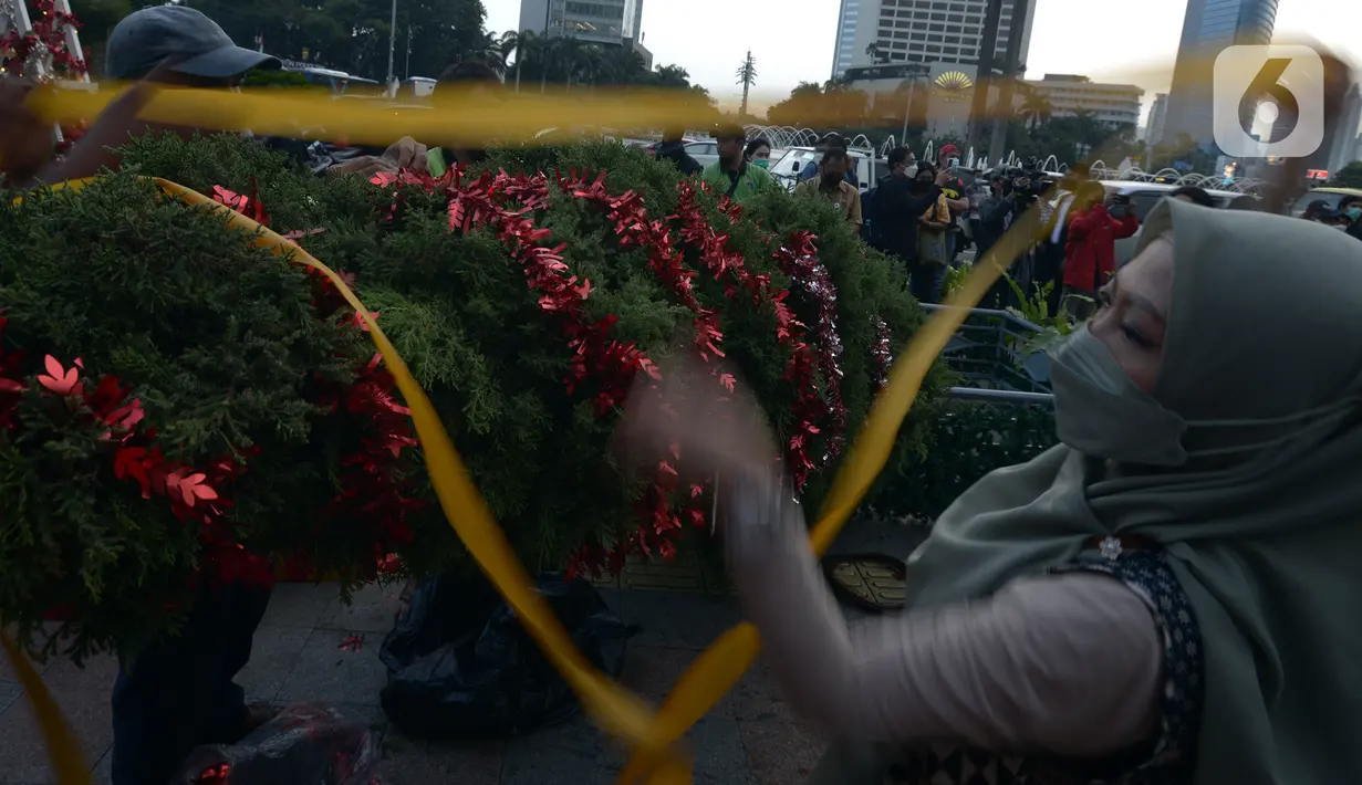 Seorang wanita menghias pohon Natal di Bundaran HI, Jakarta, Kamis (23/12/2021). Christmas Carol dilakukan di tujuh titik yang pada hari ini memasang pohon Natal di beberapa titik tersebut. (merdeka.com/Imam Buhori)