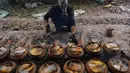 Seorang pria mengenakan masker gas saat memasak ikan di pot tanah liat menggunakan kayu bakar di provinsi Ha Nam, Vietnam, Selasa (21/1/2020). Ikan rebus adalah makanan lezat populer untuk Tahun Baru Imlek atau dikenal dengan nama Tet di utara Vietnam. (Nhac NGUYEN / AFP)