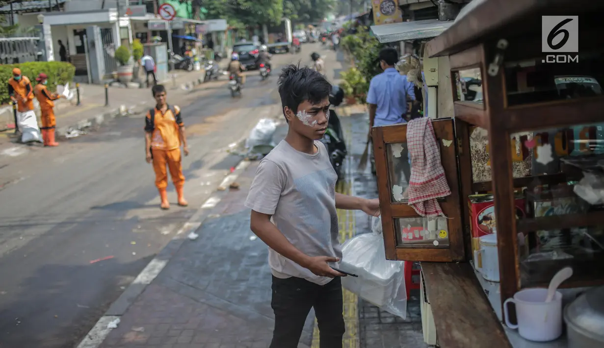 Pedagang menggunakan odol diwajah menghindari sisa gas air mata pasca bentrok massa dengan aparat di Palmerah, Jakarta, Kamis (26/9/2019). Banyak masyarakat yang melintas dan warga sekitar perih pada mata hingga bersin akibat sisa gas air mata pasca bentrokan kemarin. (Liputan6.com/Faizal Fanani)