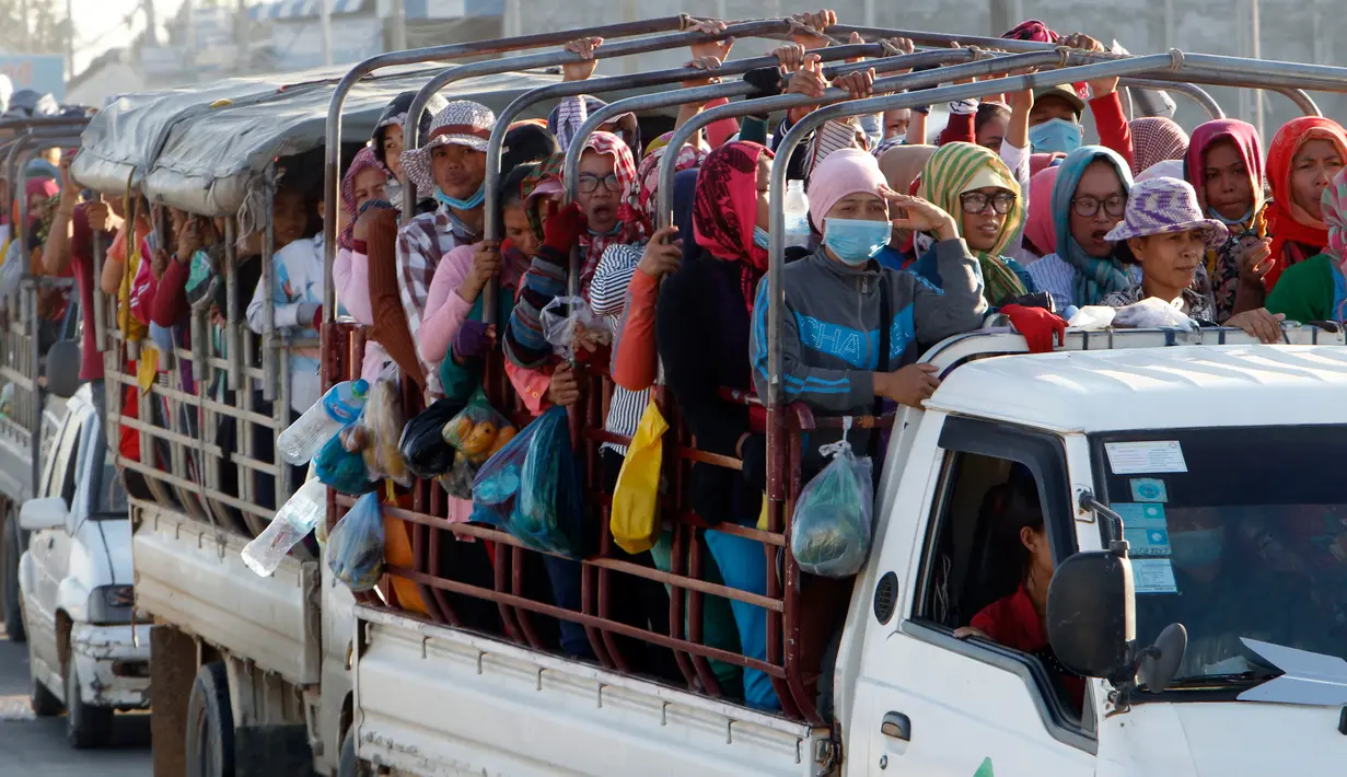 Para pekerja menaiki mobil bak terbuka sebagai transportasi harian mereka pulang ke rumah dari tempat kerja di sebuah pabrik di dekat desa Trapang Anchanh, di luar Phnom Penh, Kamboja (27/10). (AP Photo/Heng Sinith)
