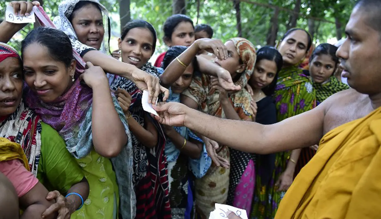 Umat muslim berebut kupon untuk mendapatkan iftar (makanan berbuka puasa) yang dibagikan para biksu di Wihara Dhammarajika, Dhaka, Bangladesh, Selasa (7/7). Ini merupakan momen langka keharmonisan umat beragama di negara Asia. (AFP PHOTO/Munir uz ZAMAN) 