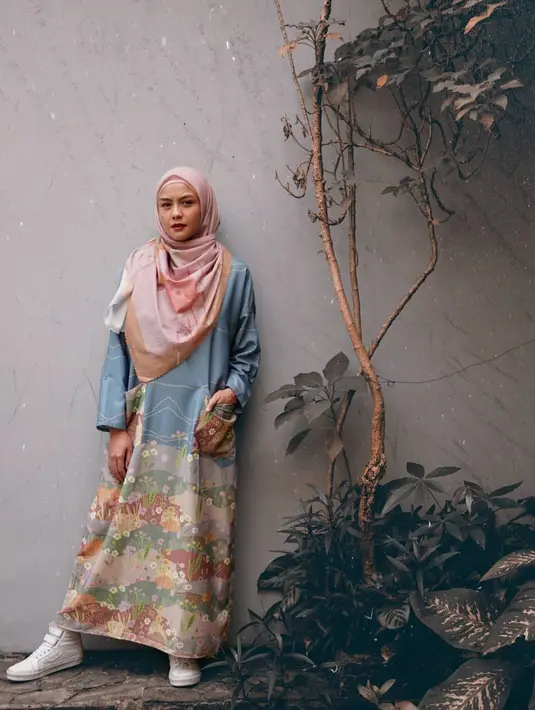 Aksen grafis pada gamis menghadirkan kesan playful. Kamu juga bisa mencuri tampilan ala Revalina dengan memakai sepatu senakers favorit. (Foto: Instagram/ Revalina Temat).