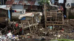 Warga bersama anak-anak di pemukiman kawasan bantaran Kali Ciliwung, Jakarta, Rabu (10/3/2021). Wagub DKI Jakarta Ahmad Riza Patria mengungkap dua kendala terkait pembebasan lahan untuk normalisasi Sungai Ciliwung, pertama status kepemilikan tanah dan anggaran. (Liputan6.com/Helmi Fithriansyah)