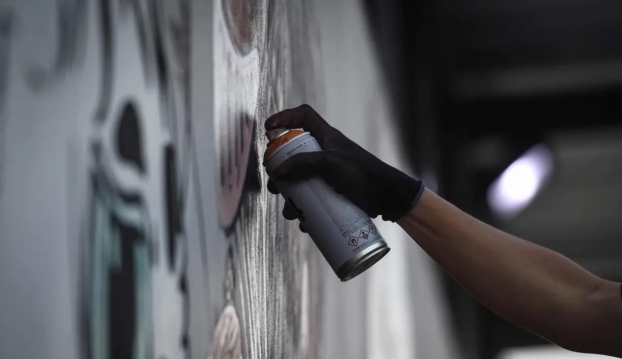 Seniman menyemprotkan cat saat membuat mural harimau kumbang di Bangkok, Thailand (16/3). Mural tersebut menggambarkan harimau kumbang duduk di sebuah meja "Perjamuan Terakhir". (AFP Photo/Lillian Suwanrumpha)