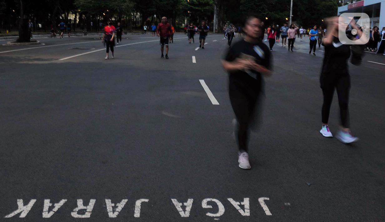 Pemberitahuan "Jaga Jarak" tertulis pada aspal saat warga berolahraga di kawasan Stadion Utama Gelora Bung Karno (SUGBK), Jakarta, Kamis (9/2/2023). Sejak pemerintah mengumumkan tidak ada lagi pembatasan sosial skala besar (PSBB), warga kian antusias untuk berolahraga seperti lari, senam, dan jalan santai. (merdeka.com/Imam Buhori)