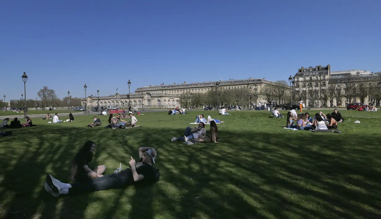 Orang-orang bersantai saat menikmati matahari di Esplanades des Invalides di Paris, Selasa (30/3/2021). Cuaca panas diperkirakan akan berlangsung selama beberapa hari di seluruh negeri. (AP Photo/Christophe Ena)