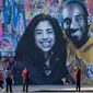 Orang-orang mengabadikan mural Kobe Bryant dan Putrinya Gigi buatan seniman Prancis Mr. Brainwash di Los Angeles (31/1/2020). Bryant memenangkan lima gelar juara NBA dan peraih medali emas Olimpiade dua kali. (AFP/Chris Delmas)