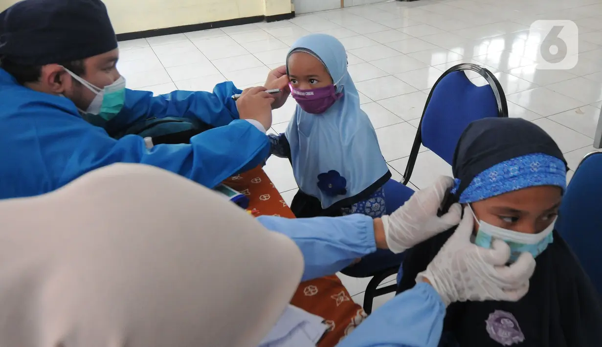 Paramedis dari Puskesmas Cinere memeriksa kesehatan murid kelas 1  saat kegiatan Bulan Imunisasi Anak Sekolah (BIAS) di SDI Al-Hidayah, Depok, Jawa Barat, Kamis (18/11/2021). Pemberian imunisasi measles rubella (MR) dan difteri tetanus (DT) berlangsung hingga Desember. (merdeka.com/Arie Basuki)