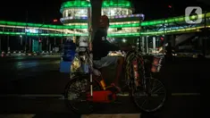 Pedagang melihat halte CSW yang berhiaskan lampu warna-warni di Kawasan Kebayoran Baru, Jakarta, Kamis (5/8/2021). Konsep desain Cakra Selaras Wahana tersebut memiliki arti sebagai lingkaran penghubung yang setara antar moda. (Liputan6.com/Johan Tallo)