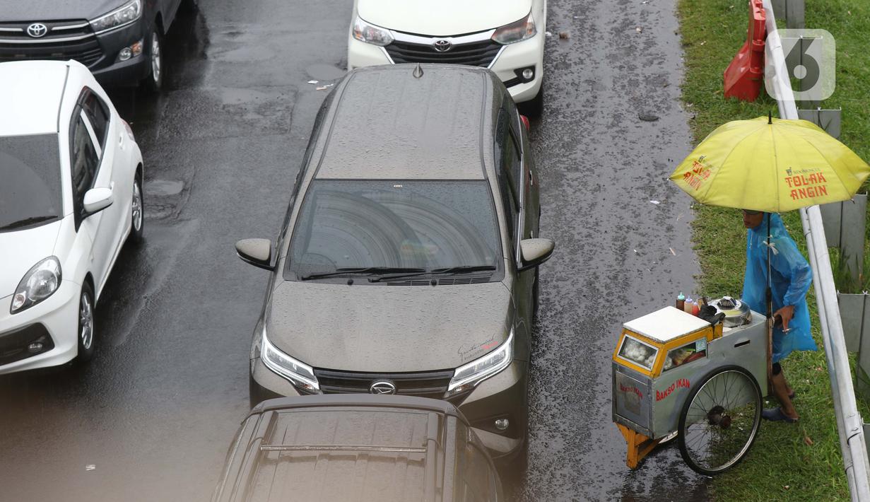 Seorang pedagang asongan menawarkan dagangan kepada pengendara di jalan tol Jagorawi yang sedang menanti waktu buka tutup jalur menuju kawasan wisata puncak, Bogor, Jawa Barat, Sabtu (31/10/2020). (Liputan6.com/Helmi Fithriansyah)