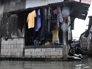 Warga beraktivitas saat banjir rob menggenangi permukiman Muara Angke, Jakarta, Selasa (22/1). Banjir air laut pasang atau Rob yang kembali melanda kawasan itu sejak 6 hari lalu membuat aktivitas warga sekitar terganggu. (Merdeka.com/Iqbal S. Nugroho)