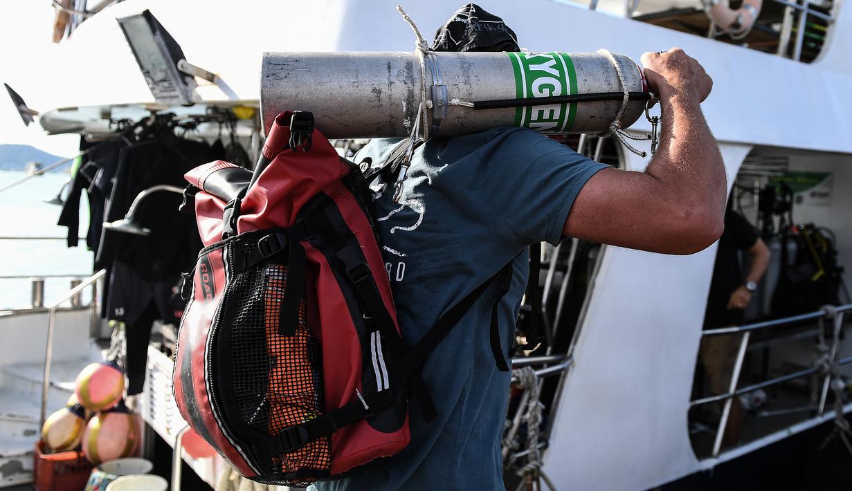 Penyelam membawa tangki oksigen untuk melanjutkan pencarian korban kapal wisata yang terbalik di dermaga Chalong, Phuket, Sabtu (7/7). Kapal Phoenix diketahui dihantam gelombang setinggi lima meter saat badai Kamis malam. (AFP/Mohd RASFAN)