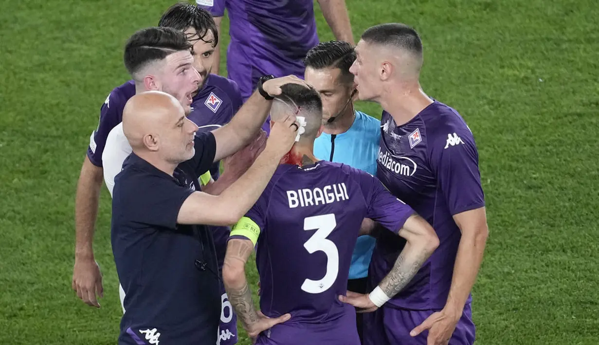 Pemain Fiorentina, Cristiano Biraghi, mendapat perawatan akibat menderita luka di bagian kepala setelah insiden pelemparan benda dari tribun suporter West Ham United pada laga final UEFA Europa Conference League di Stadion Eden Arena, Kamis (8/6/2023). Fiorentina takluk dengan skor 1-2. (AP Photo/Darko Vojinovic)
