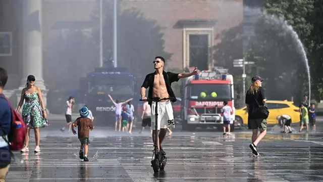 Di tengah gelombang panas ekstrem, polisi mengerahkan meriam air untuk membantu mendinginkan warga di Lapangan Heroes, Budapest, Hungaria.