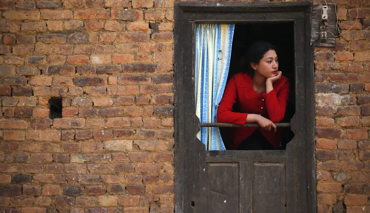 Seorang wanita menonton festival Swasthani Bratakatha, Nepal , (19/2). Kaum wanita diwajibkan berpuasa yang dipercaya mampu mensejahterakan keluarga mereka dan yang tidak memiliki pasangan akan mendapatkan jodoh yang baik. (REUTERS / Navesh Chitrakar)