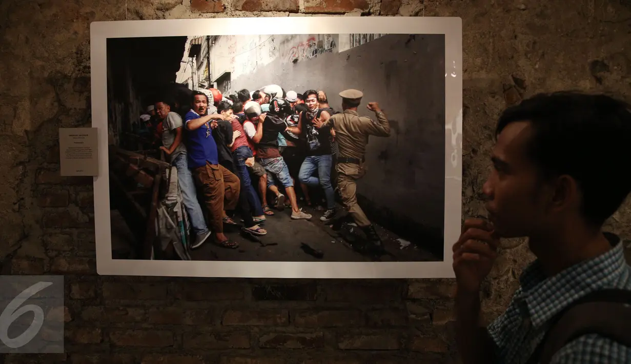 Pengunjung di depan sebuah foto saat pameran foto Anugerah Pewarta Foto Indonesia (APFI) ke-VI di Gedung De Vries, Bandung, Sabtu (9/4). APFI 2016 memamerkan 25 foto tunggal dan tiga foto seri terbaik sepanjang tahun 2015. (Liputan6.com/Faizal Fanani)