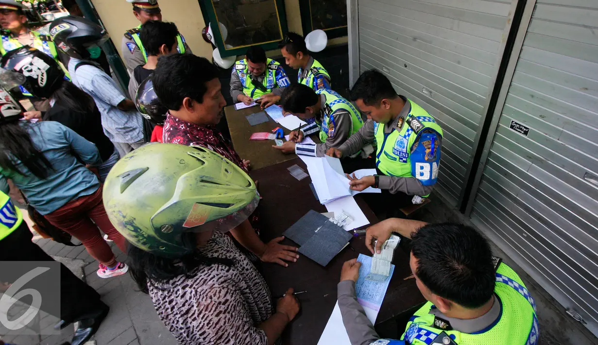 Petugas menulis surat tilang pada operasi lintas di Abu Bakar Ali,Yogyakarta, (19/5). Operasi ini untuk menekan angka kecelakaan, petugas memberikan surat tilang di tempat kepada pelanggar lalu lintas. (Liputan6.com/Boy Harjanto)