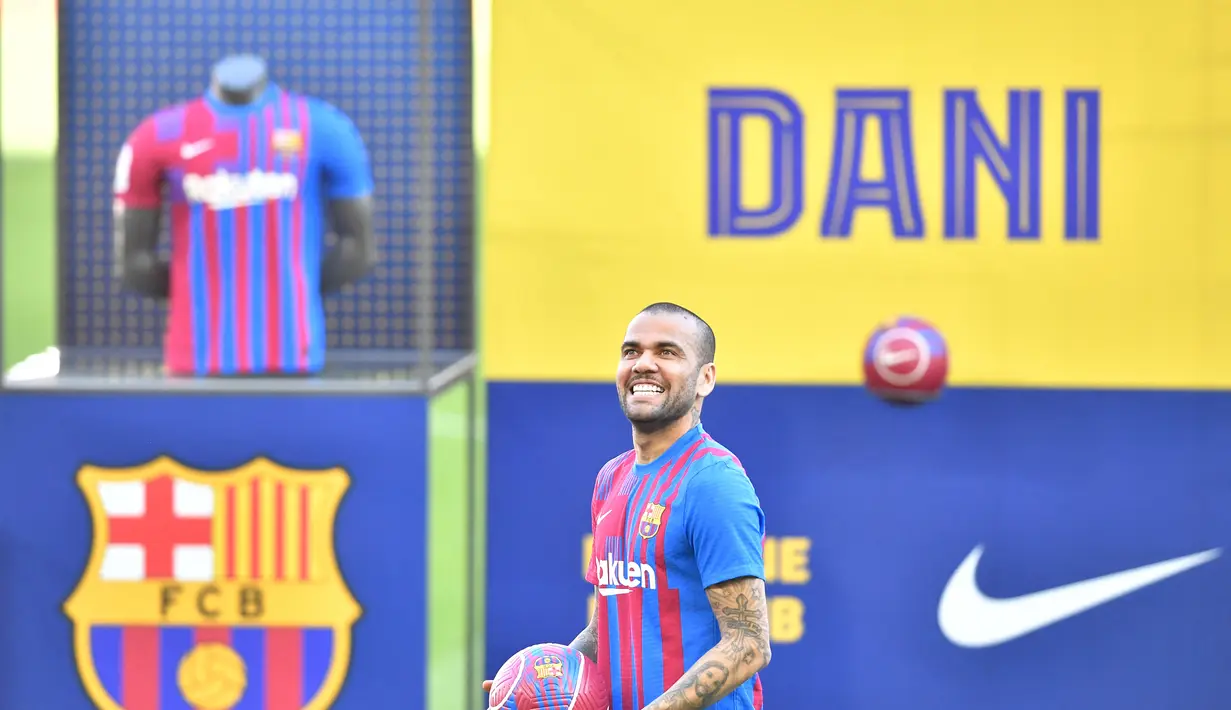 Bek baru Barcelona Brasil Dani Alves tersenyum selama upacara presentasi di stadion Camp Nou di Barcelona (17/11/2021). Dani Alves resmi diperkenalkan sebagai rekrutan anyar Barcelona di Stadion Camp Nou, Rabu (17/11) malam WIB. (AFP/Pau Barrena)