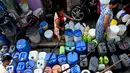 Warga mengumpulkan air dari truk tangki air perusahaan kota di lingkungan berpenghasilan rendah di New Delhi pada Kamis (3/6/2021). Masalah air bersih di India bukan hal baru, ratusan ribu orang mengantre setiap hari untuk mengisi ember dari truk air pemerintah. (Money SHARMA / AFP)