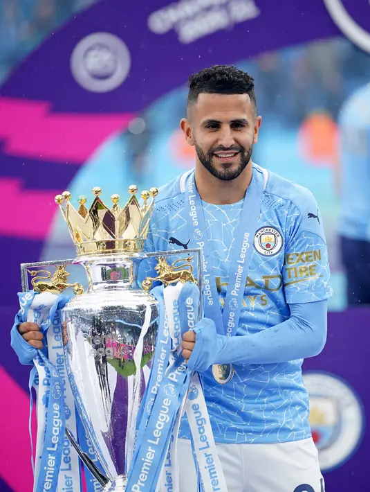 Gelandang Manchester City, Riyad Mahrez berpose dengan trofi Liga Inggris saat merayakan timnya meraih juara usai mengalahkan Everton di stadion Etihad di Manchester, Minggu (23/5/2021). (AFP Photo/Pool/Dave Thompson)