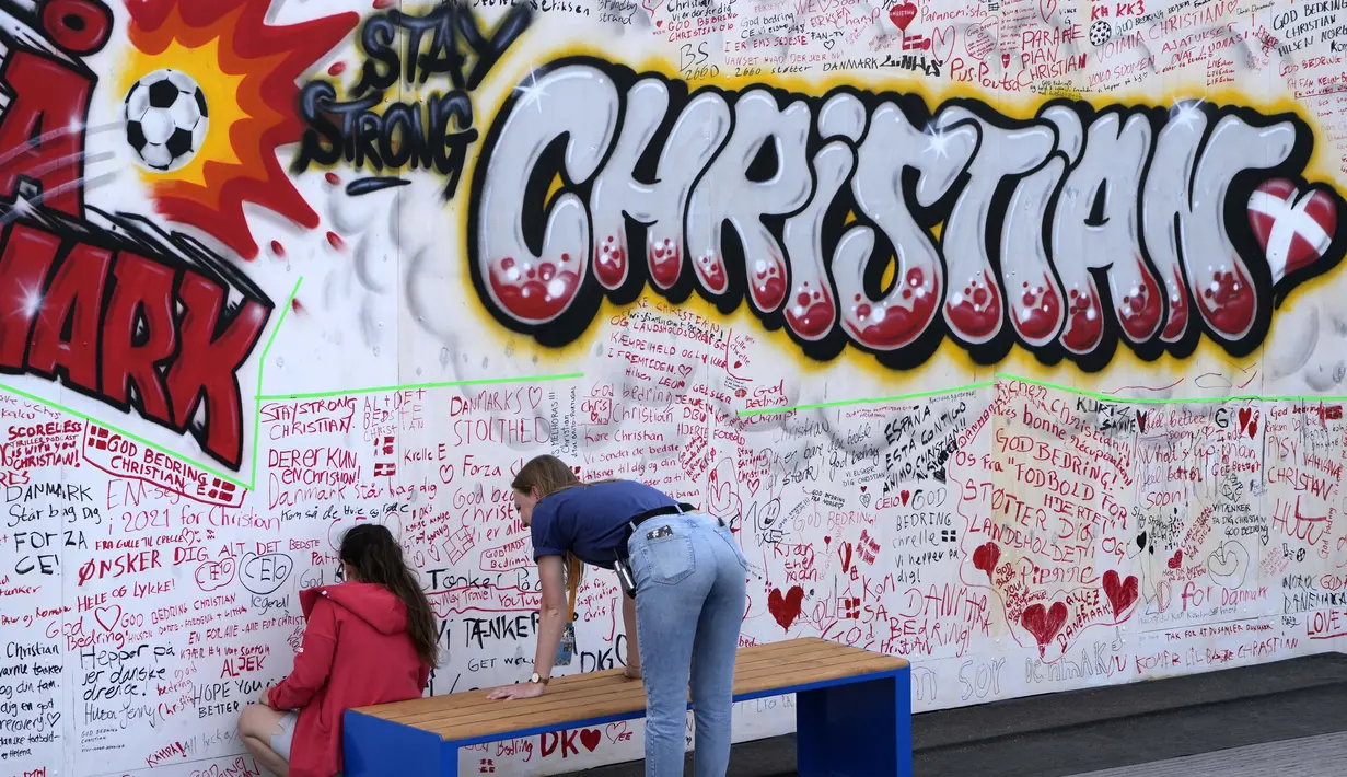 Orang-orang meninggalkan harapan baik pada mural untuk gelandang timnas Denmark Christian Eriksen di dinding fanzone di Kopenhagen, Senin (14/6/2021). Eriksen mengalami serangan jantung dan sempat tak sadarkan diri saat memperkuat timnas Denmark vs Finlandia di Euro 2020. (AP Photo/Martin Meissner)