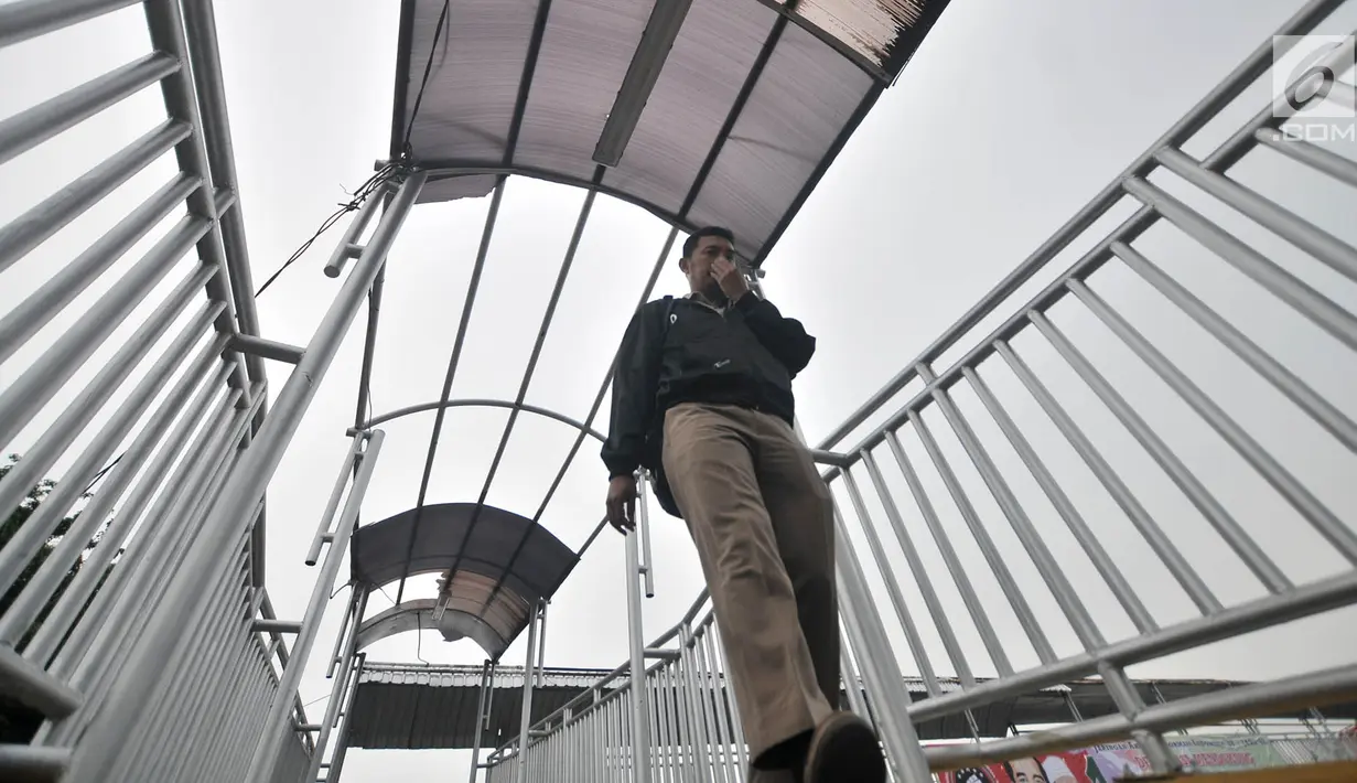 Pejalan kaki melintasi jembatan penyeberangan orang (JPO) di Jalan Yos Sudarso, Jakarta, Kamis (8/11). Selain rusak pada bagian atap, besi pada JPO tersebut juga sudah berkarat. (Merdeka.com/Iqbal Nugroho)