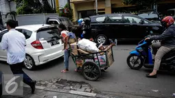 Ditengah kemacetan Jakarta seorang ibu membawa dua orang anaknya bersama dengan gerobak yang berisi barang bekas, mengitari jalan mengumpulkan barang bekas yang di bisa dijual, Jakarta, Kamis (6/10). (Liputan6.com/Faizal Fanani)