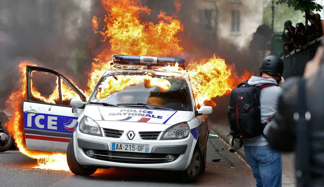 Sebuah mobil polisi terbakar saat demonstrasi buruh di Paris, Prancis (18/5). Demo buruh tersebut menentang kekerasan polisi dan melawan reformasi hukum yang berakhir bentrok dengan polisi. (REUTERS / Charles Platiau)
