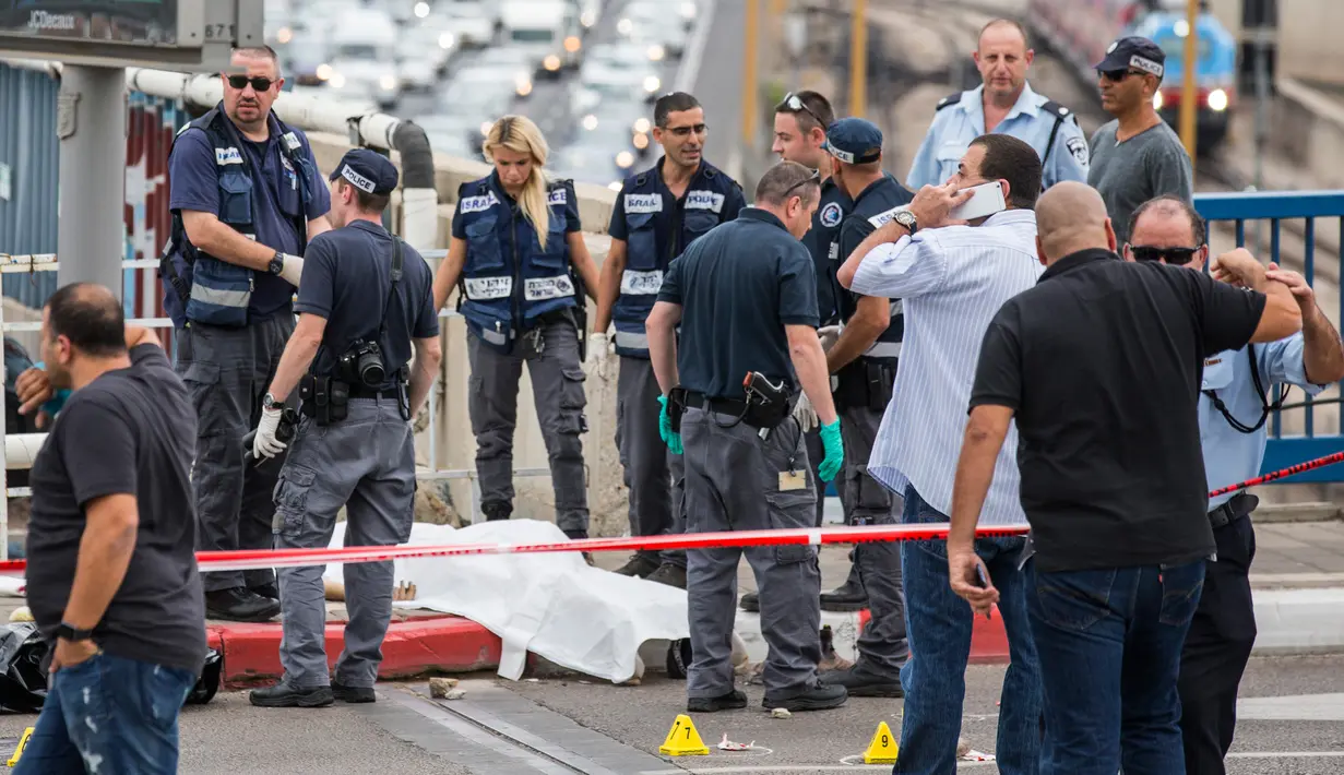 Polisi Israel memeriksa mayat pria Palestina yang ditembak mati usai menikam dua warga Israel di Tel Aviv, Kamis (8/10). Menurut juru bicara polisi Israel, pria Palestina itu menikam tentara wanita dengan obeng di Mulailah Street. (AFP PHOTO/JACK GUEZ)