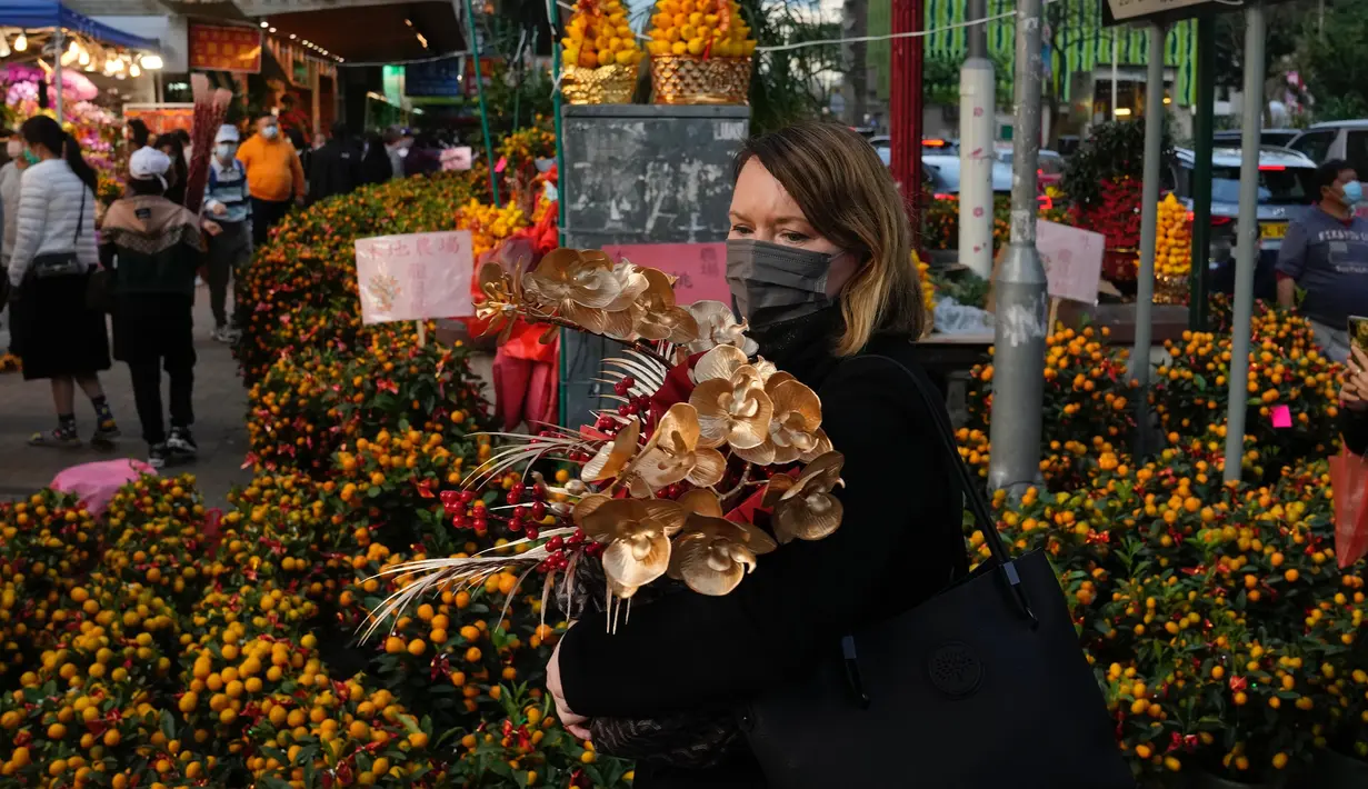 Seorang wanita membeli bunga untuk merayakan Tahun Baru Imlek di Hong Kong, Rabu (19/1/2022). Tahun Baru Imlek China jatuh pada 1 Februari 2022. (AP Photo/Kin Cheung)