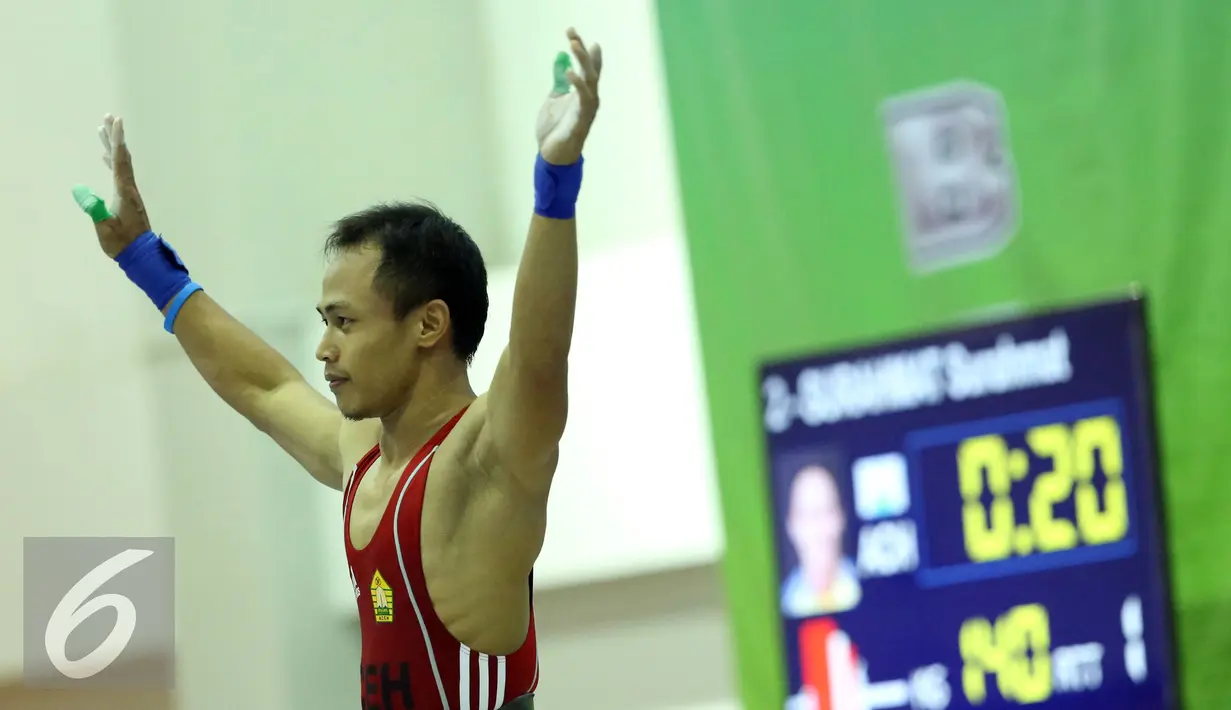 Lifter Nanggroe Aceh Darussalam, Surahmat mengangkat tangan usai melakukan angkatan clean and jerk di kelas 56kg PON XIX Jabar di Gymnasium Si Jalak Harupat, Kab Bandung, Selasa (20/9). Surahmat meraih emas. (Liputan6.com/Helmi Fithriansyah)