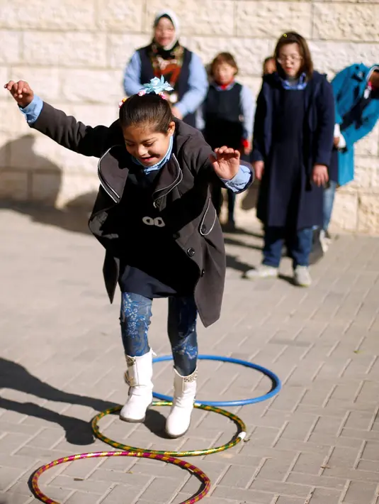 Seorang murid bermain ditemani gurunya, Hiba Al-Sharfa di sekolah Asosiasi Hak Hidup di Kota Gaza (21/12). Hiba bekerja untuk membantu mendidik dan merehabilitasi anak-anak dengan kondisi tersebut. (Reuters/Suhaib Salem)